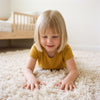 Young girl pressing her hands into a soft rug, sensory toys category