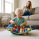 Toddler playing with the blue dinosaur felt busy board while his mother drinks her coffee