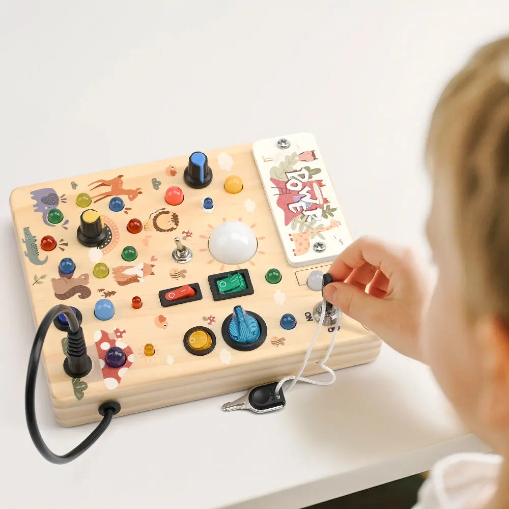 Toddler turning the chrome key switch on the forest LED busy board