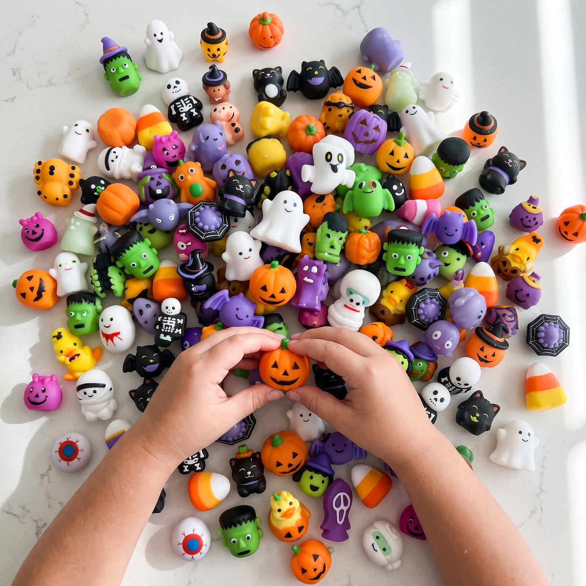 Top-down view of a large pile of Halloween mochi squishies including carved pumpkins, white ghosts, skeletons, black cats, green Frankensteins and candy corn