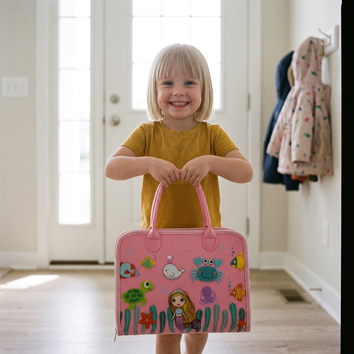 Girl carrying the pink felt busy board by its two handles like a small bag
