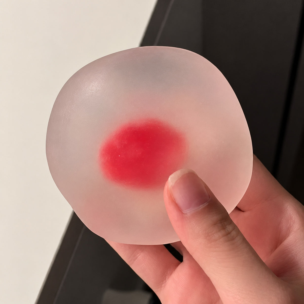 Crystal strawberry squishy held in one hand, thumb pressing in