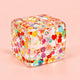 Clear fruit ice cube squishy packed with fruit slices, on a plain peach background
