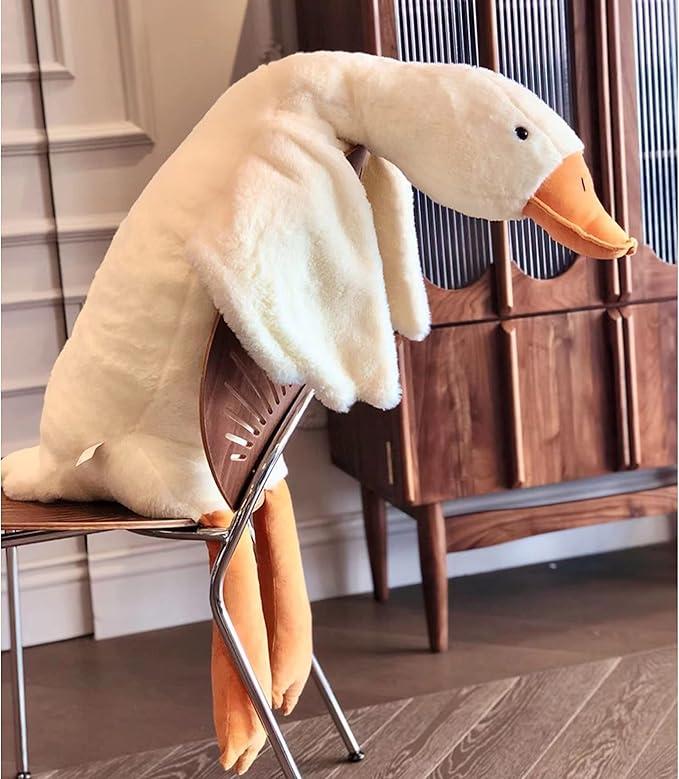 Large white goose plush with an orange beak draped over a dining chair