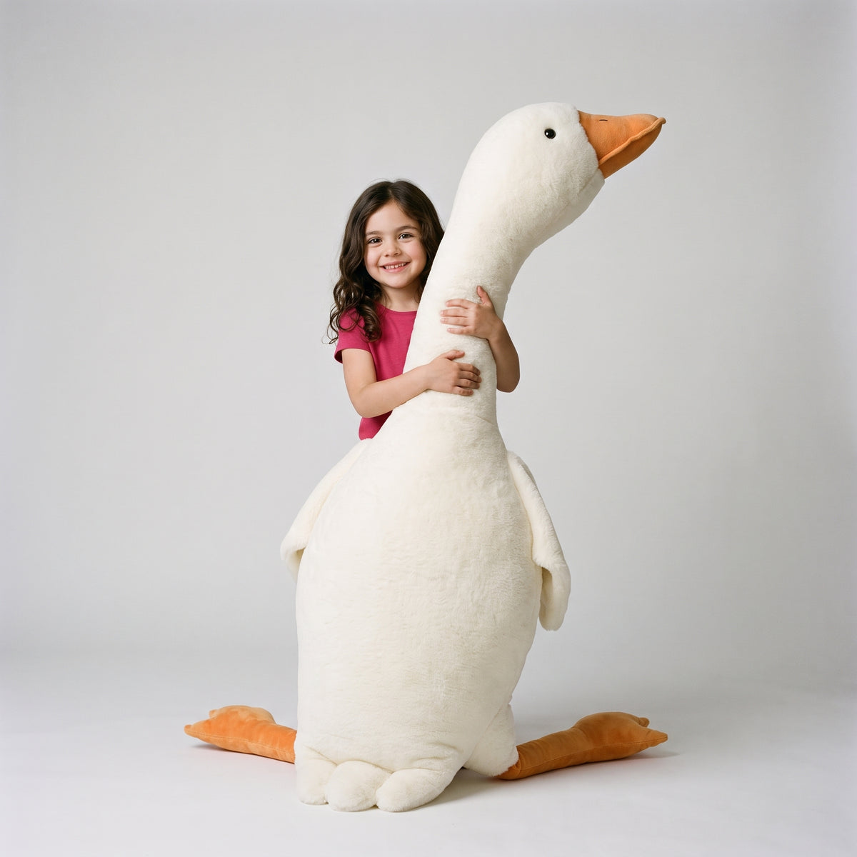 A six year old girl hugging the giant goose plush, which stands taller than she is