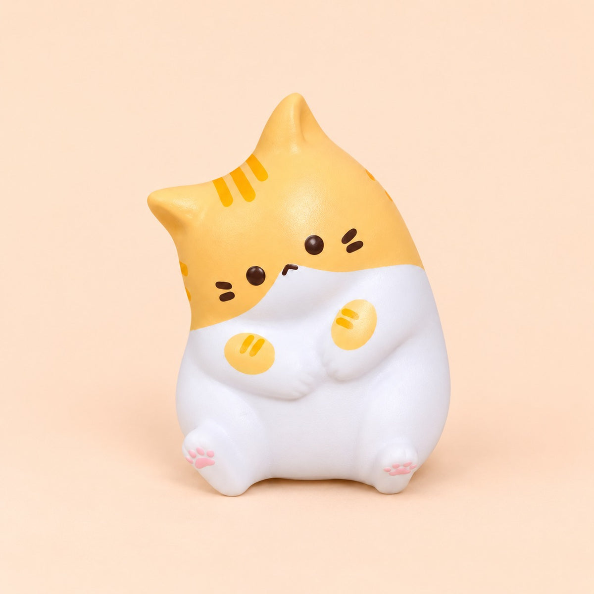 Orange tabby kawaii cat squishy sitting up on a plain peach background