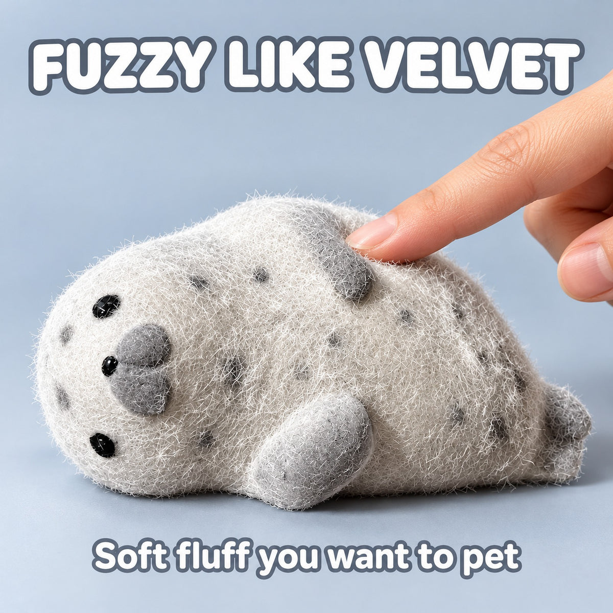 Fingertip stroking the fuzzy coat of the grey seal squishy, text Fuzzy like velvet