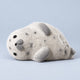 Grey spotted fuzzy seal squishy lying on a plain pale blue background