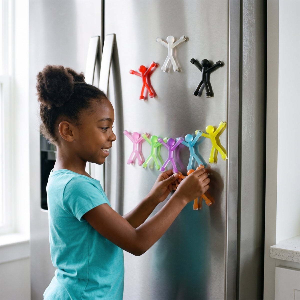 A girl hanging a chain of magnetic stick figures on the stainless fridge door