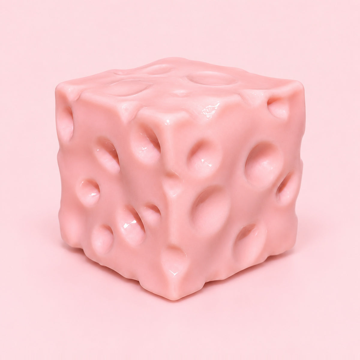 Pink moldable cheese squishy block with holes on a plain pink background
