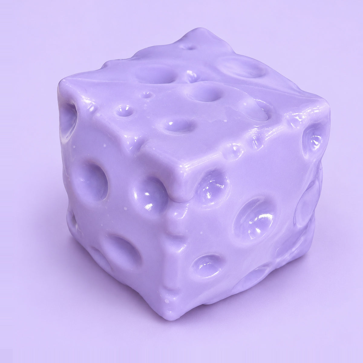 Purple moldable cheese squishy block with holes on a plain lavender background