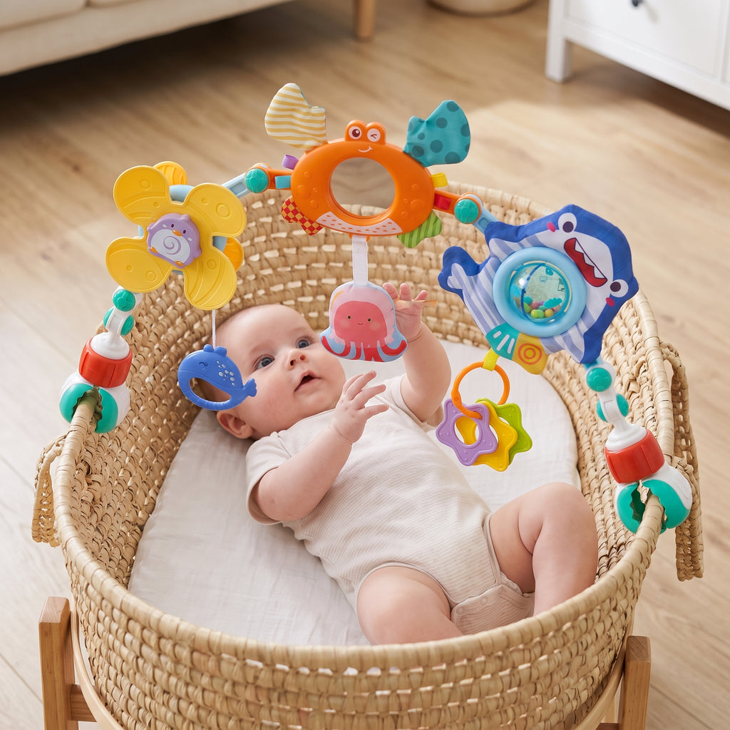 Play arch clipped to the rim of a wicker bassinet, baby grabbing the octopus