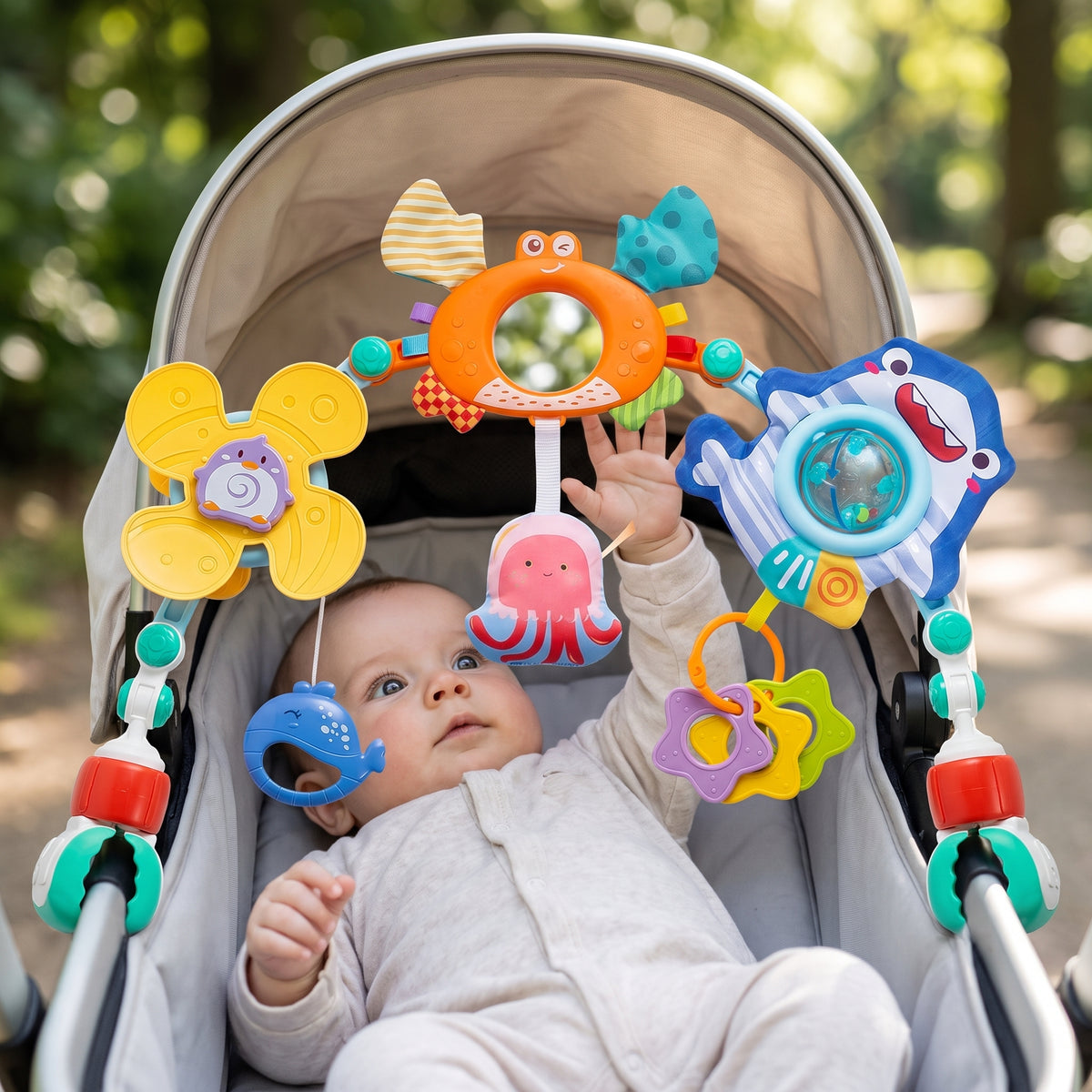 Play arch clipped to a stroller bar, baby looking up at the hanging toys