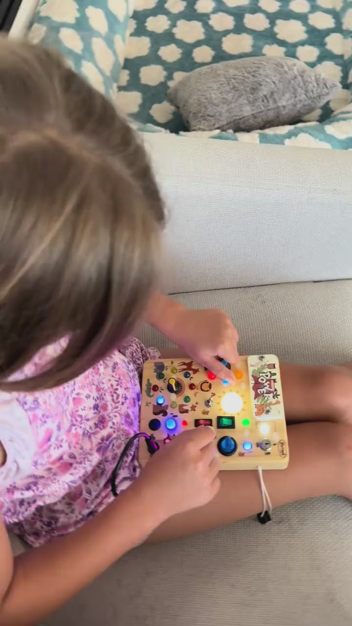 Toddler flicking the switches of the forest LED busy board and lighting the bulbs
