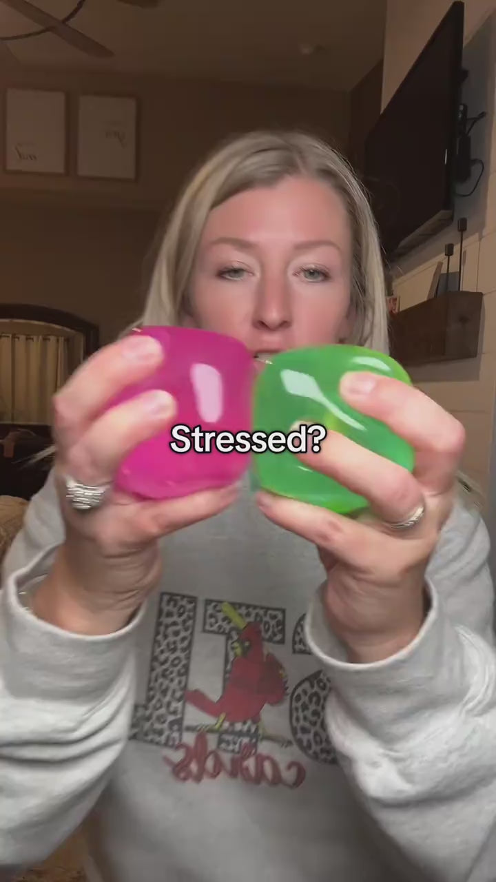 Squeezing and pulling clear green and pink squishy cubes
