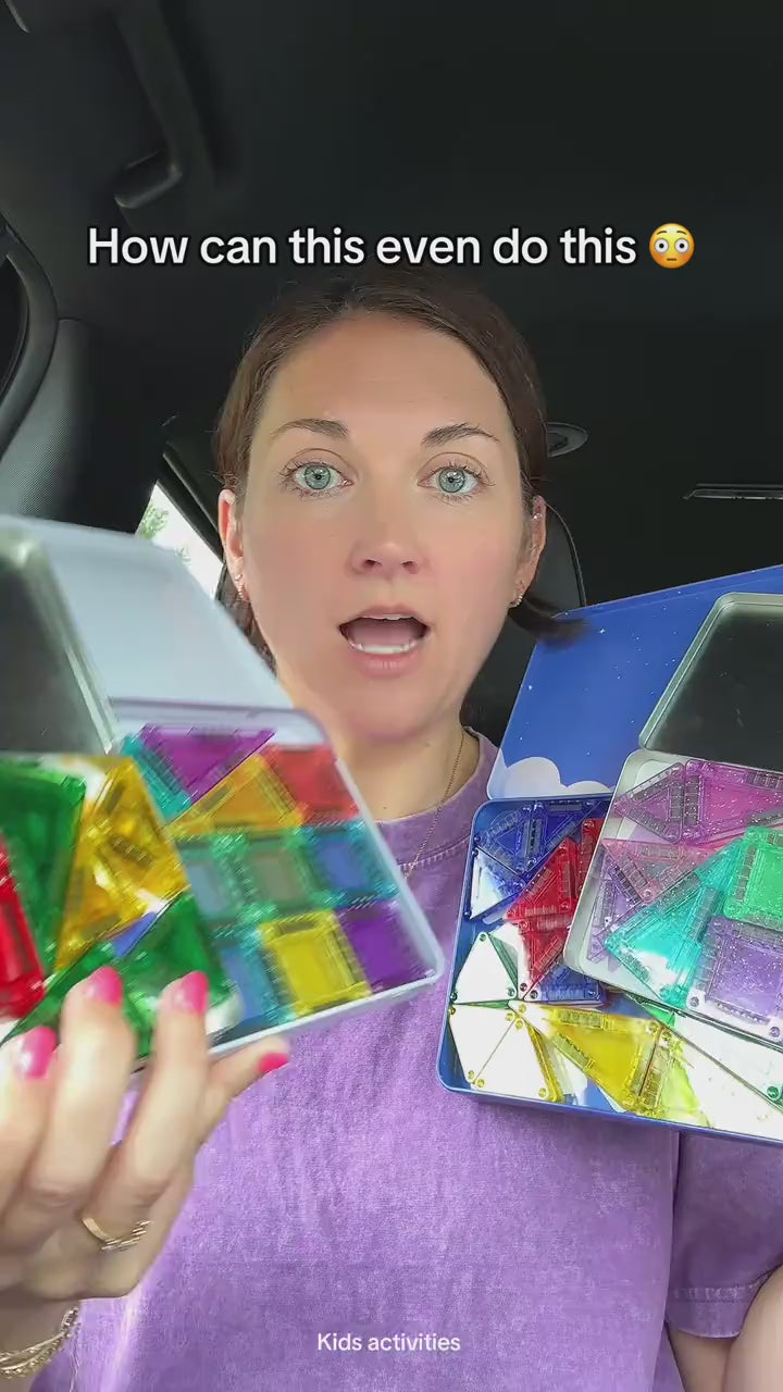 Mother holding open the flat metal tin of 40 mini magnetic tiles and a tile held up to the light