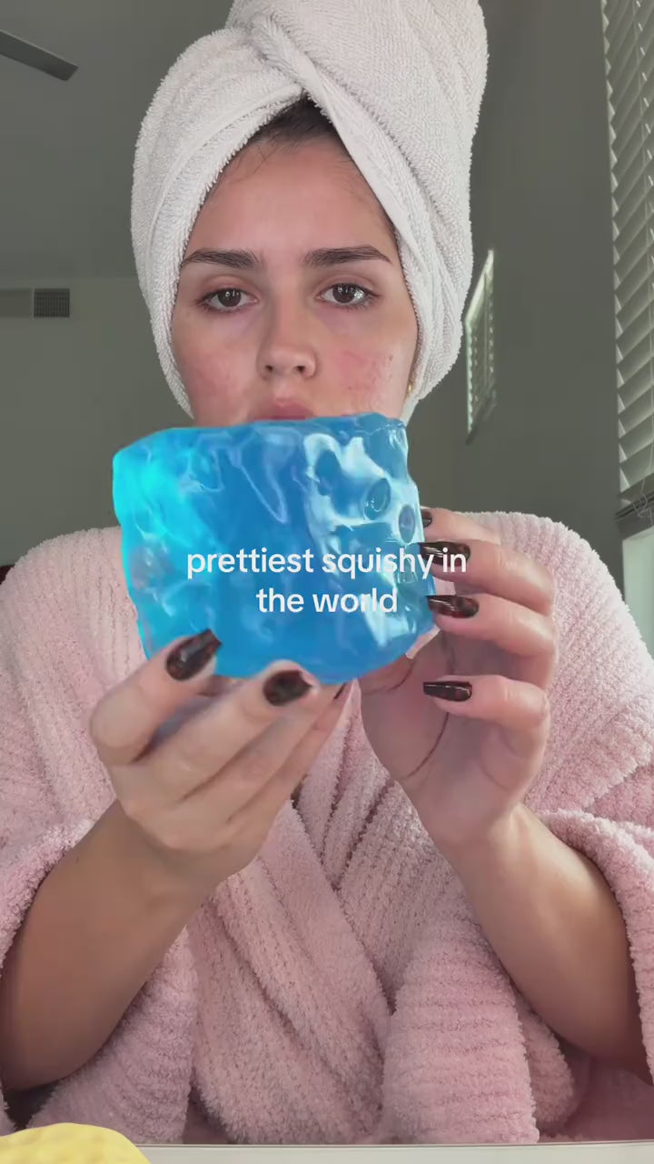 Hands pressing the jumbo blue jelly cheese cube squishy into new shapes