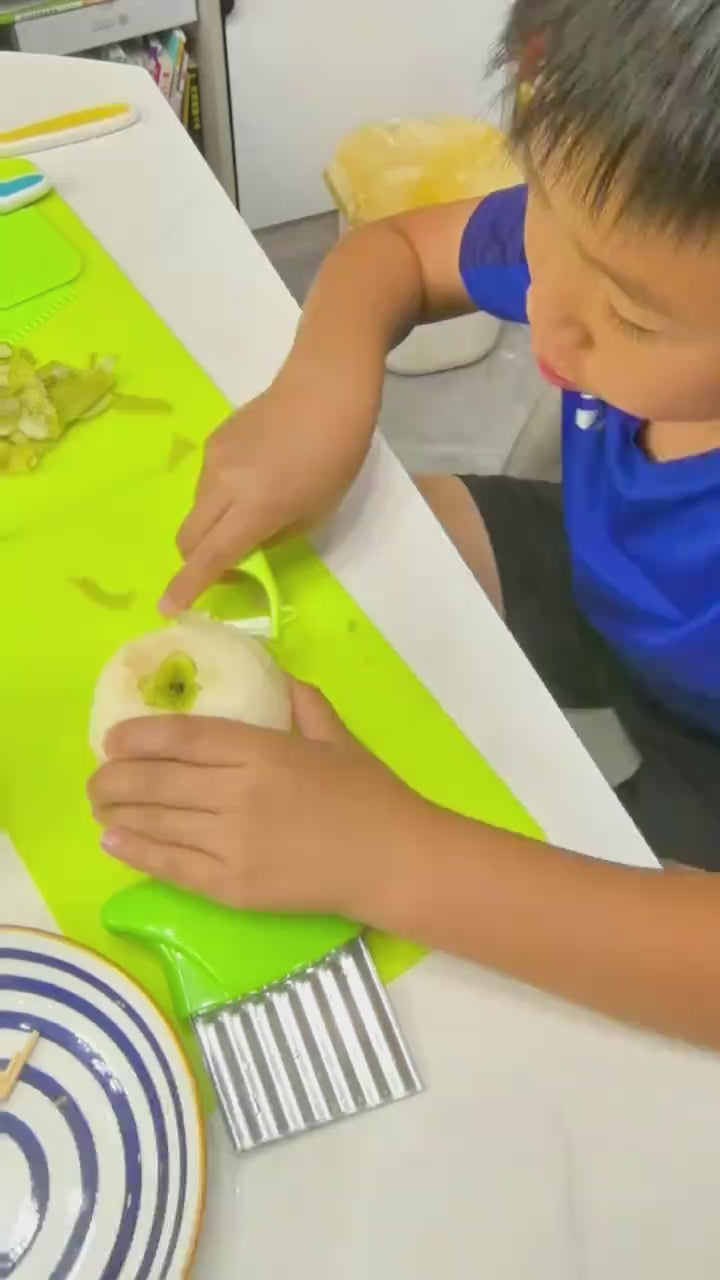 A child using the kitchen set on their own: the nylon knife, the peeler, the crinkle cutter and the shape cutters