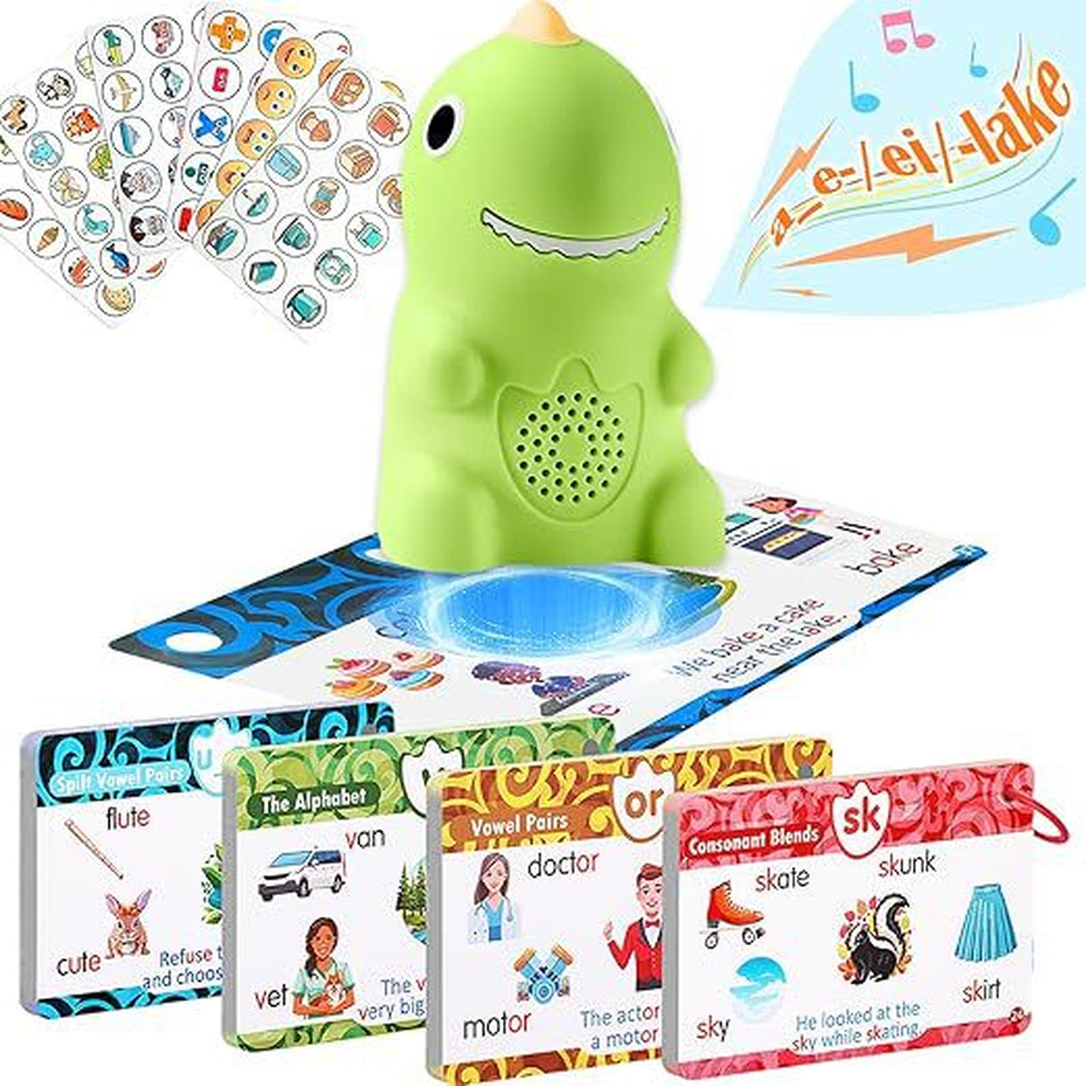 Everything in the set laid out on white: the green dinosaur reader standing on a phonics card, four sheets of peel-off picture stickers, and four of the ring-bound card sets
