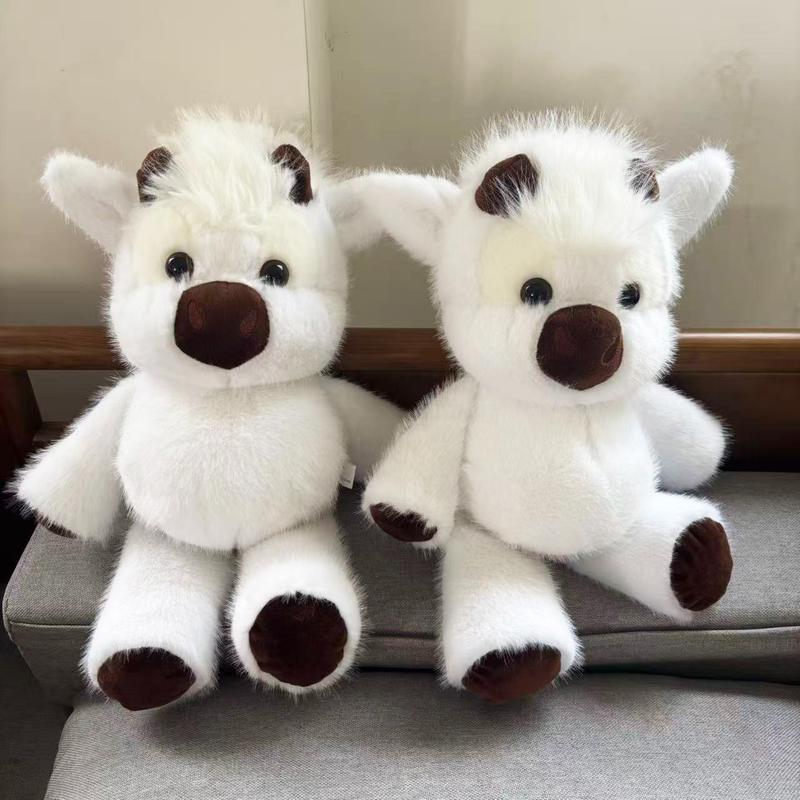 Two white Highland cow plush toys sitting side by side on a sofa