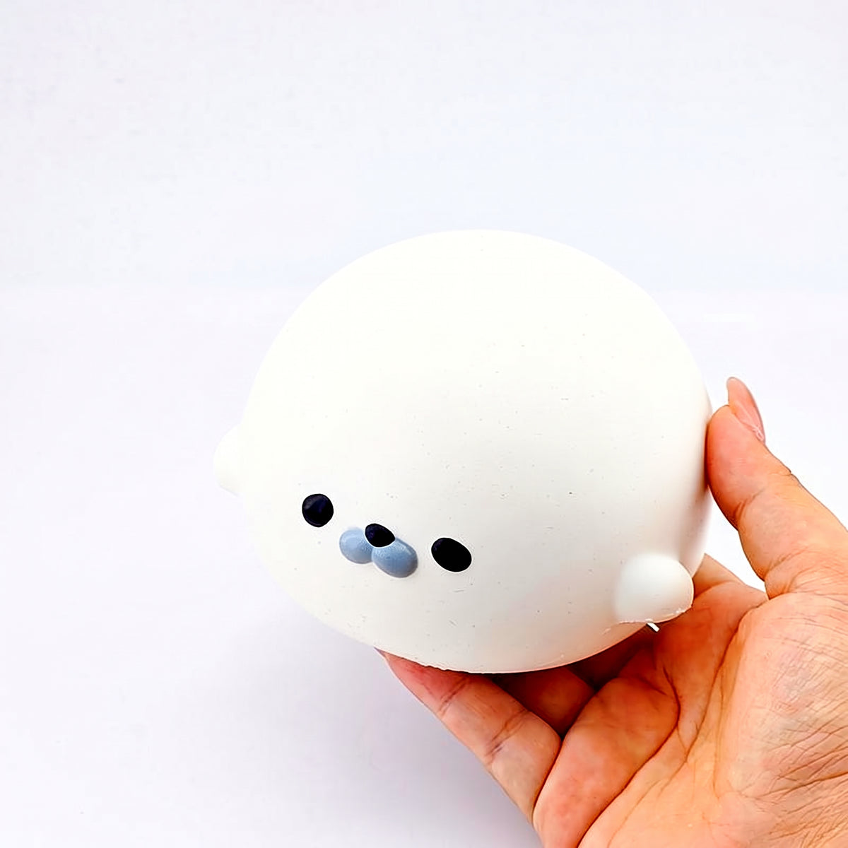 White seal squishy held in an open hand, showing its size