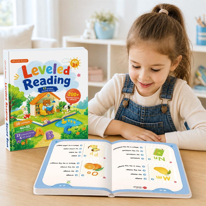 A girl reading the talking phonics book at a table, cover standing beside it